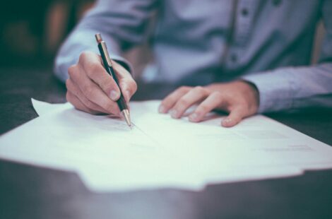 Une personne qui signe sur un papier avec un stylo